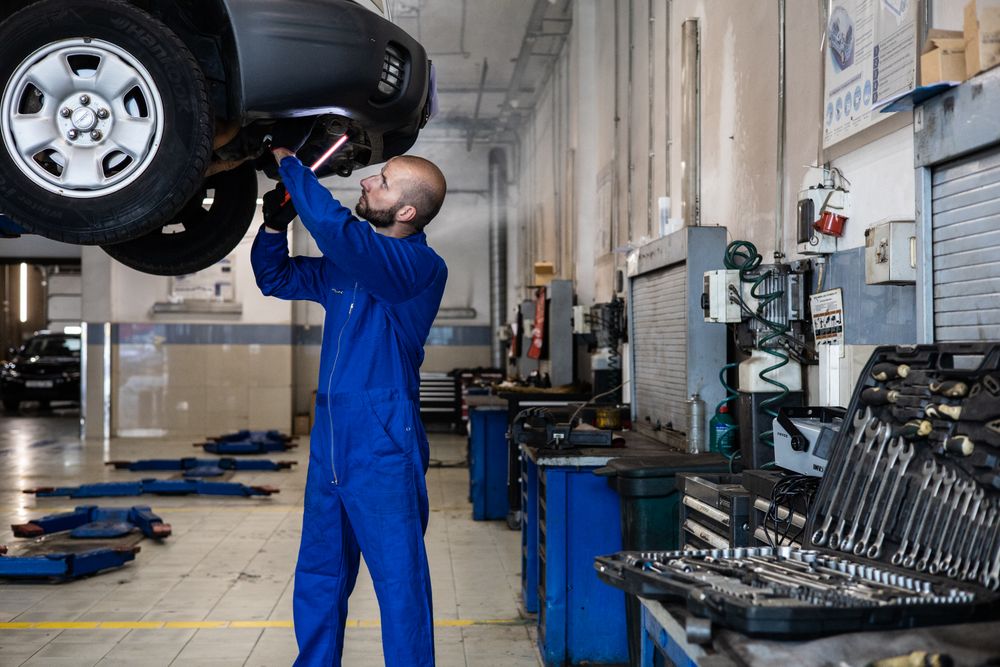 Mechanic inspecting the underside of a car on a lift